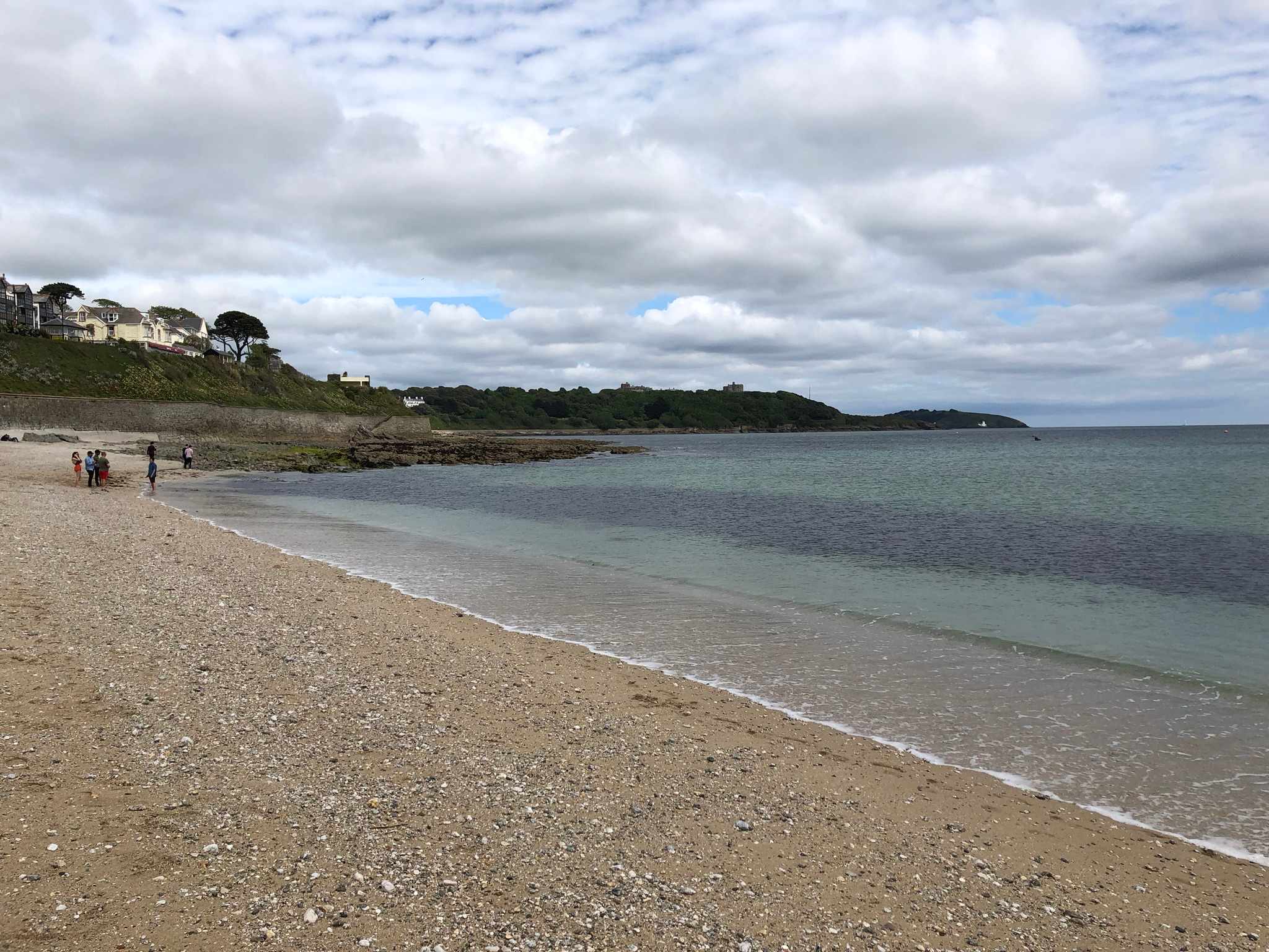 Gyllyngvase Beach at Falmouth on a clear afternoon — south-facing, Blue Flag, with Pendennis Castle on the headland in the distance.