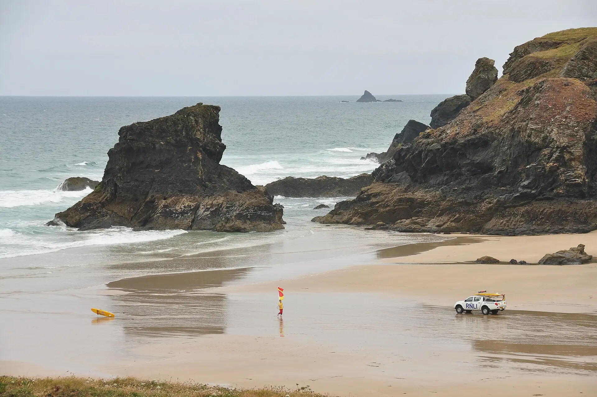 Porthcothan bay at low tide, firm sand stretching between sheltering cliffs.