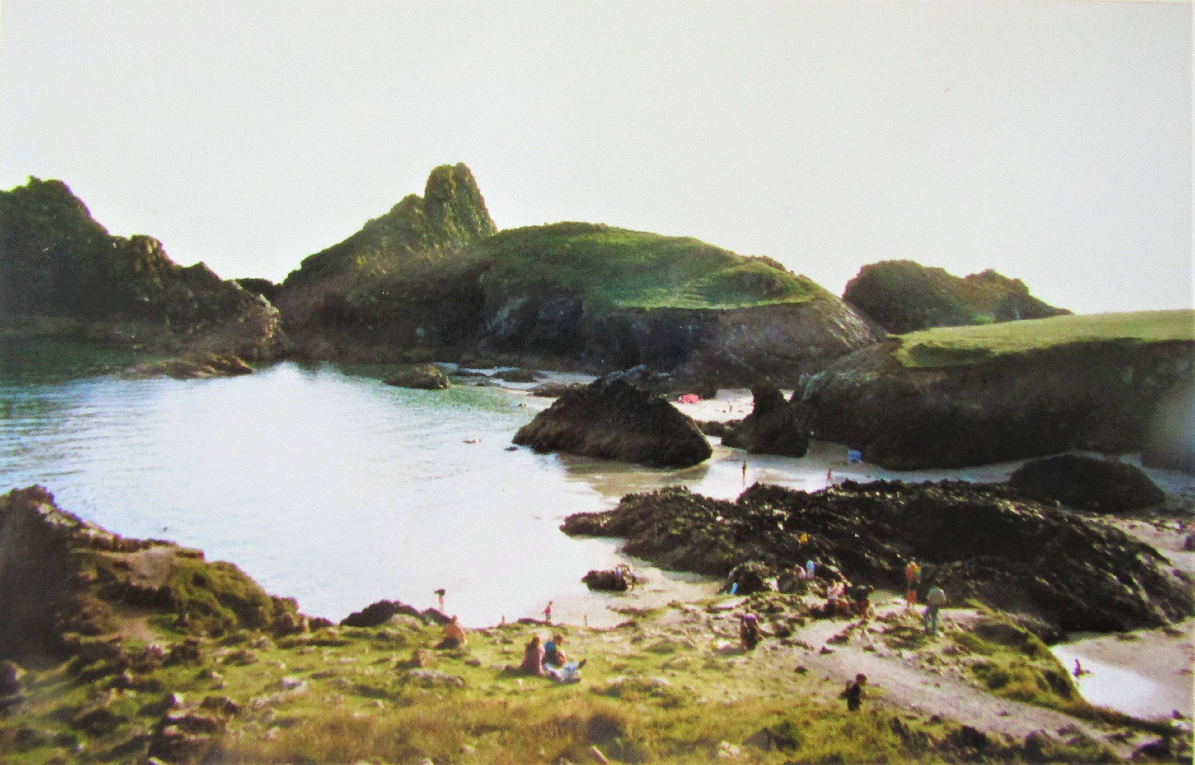Kynance Cove in winter — turquoise water and dark serpentine rock stacks under dramatic winter clouds.