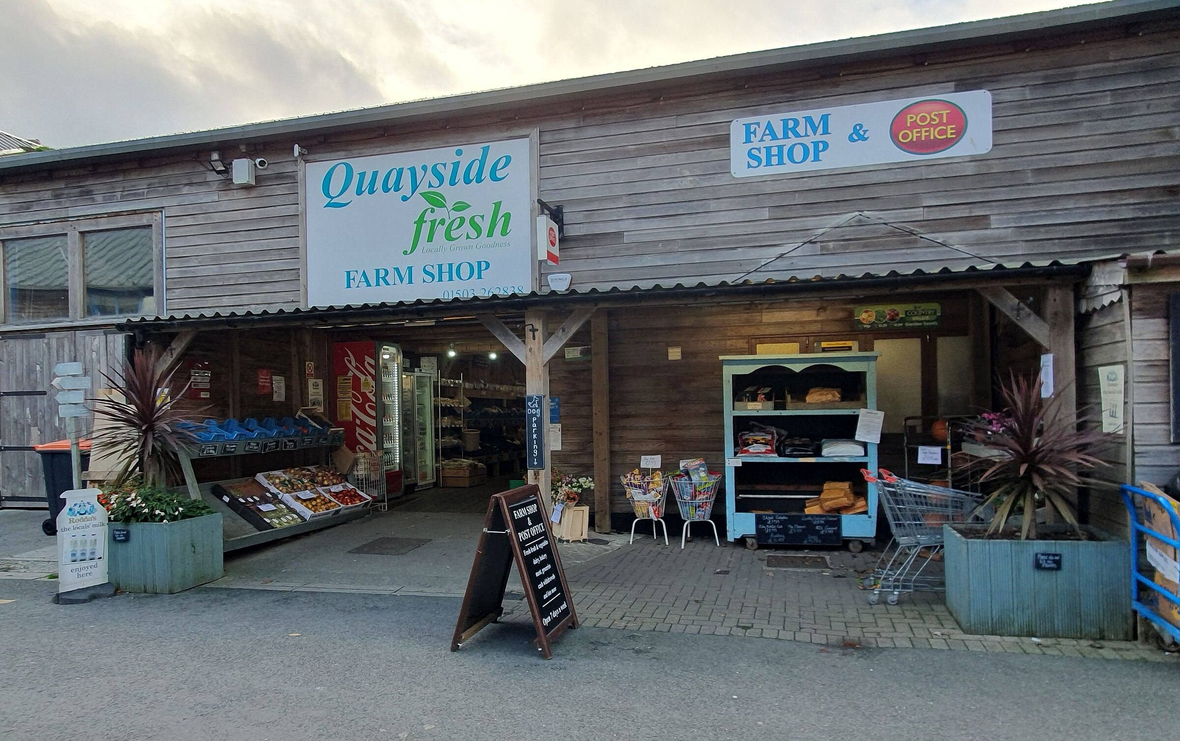 A Cornish farm shop interior — shelves of local jams, chutneys, baked goods and a wooden chalkboard listing what's been picked or baked that morning.