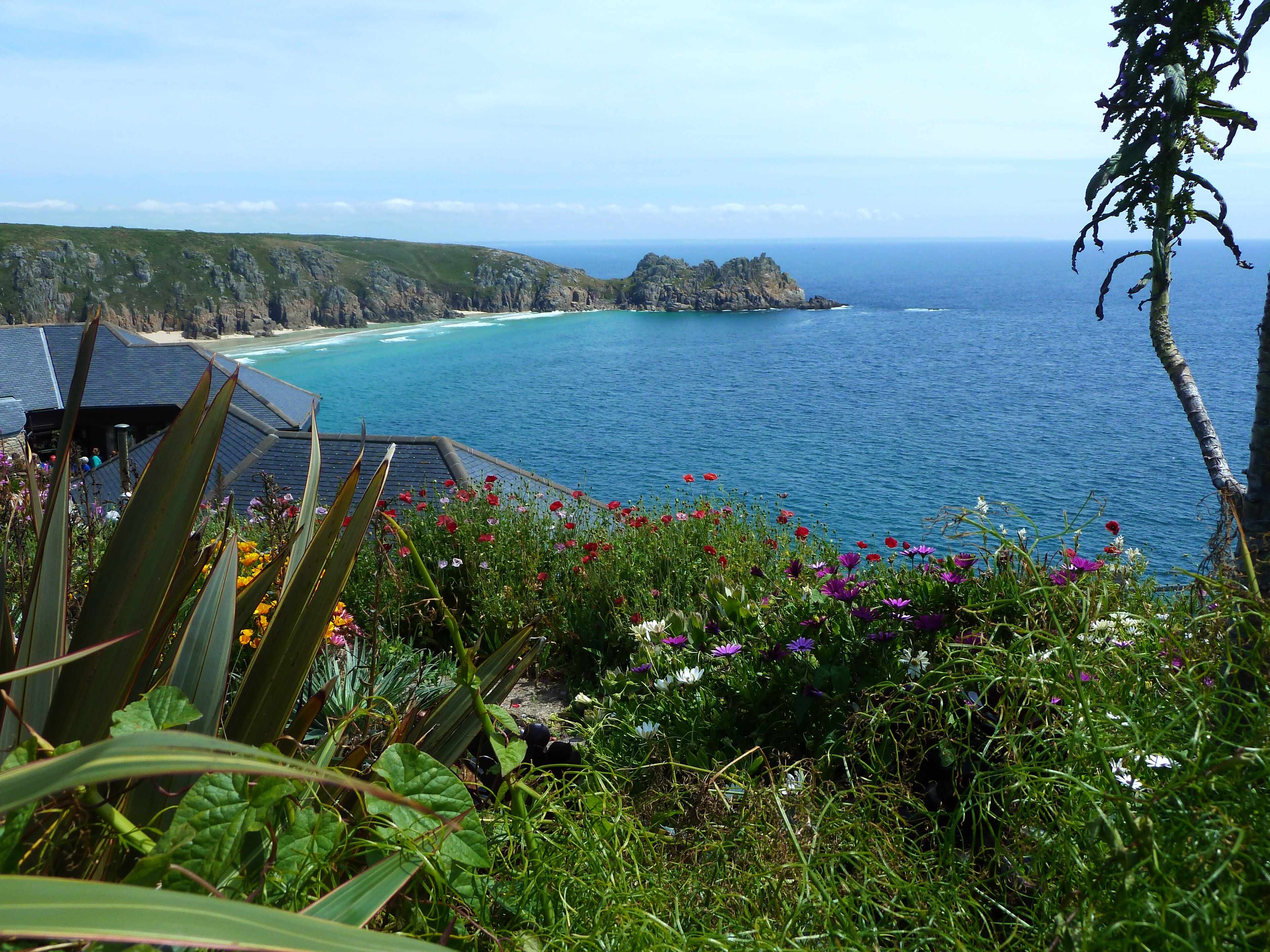 The Minack Theatre cut into the cliff above Porthcurno, with a summer evening performance under a clear sky.
