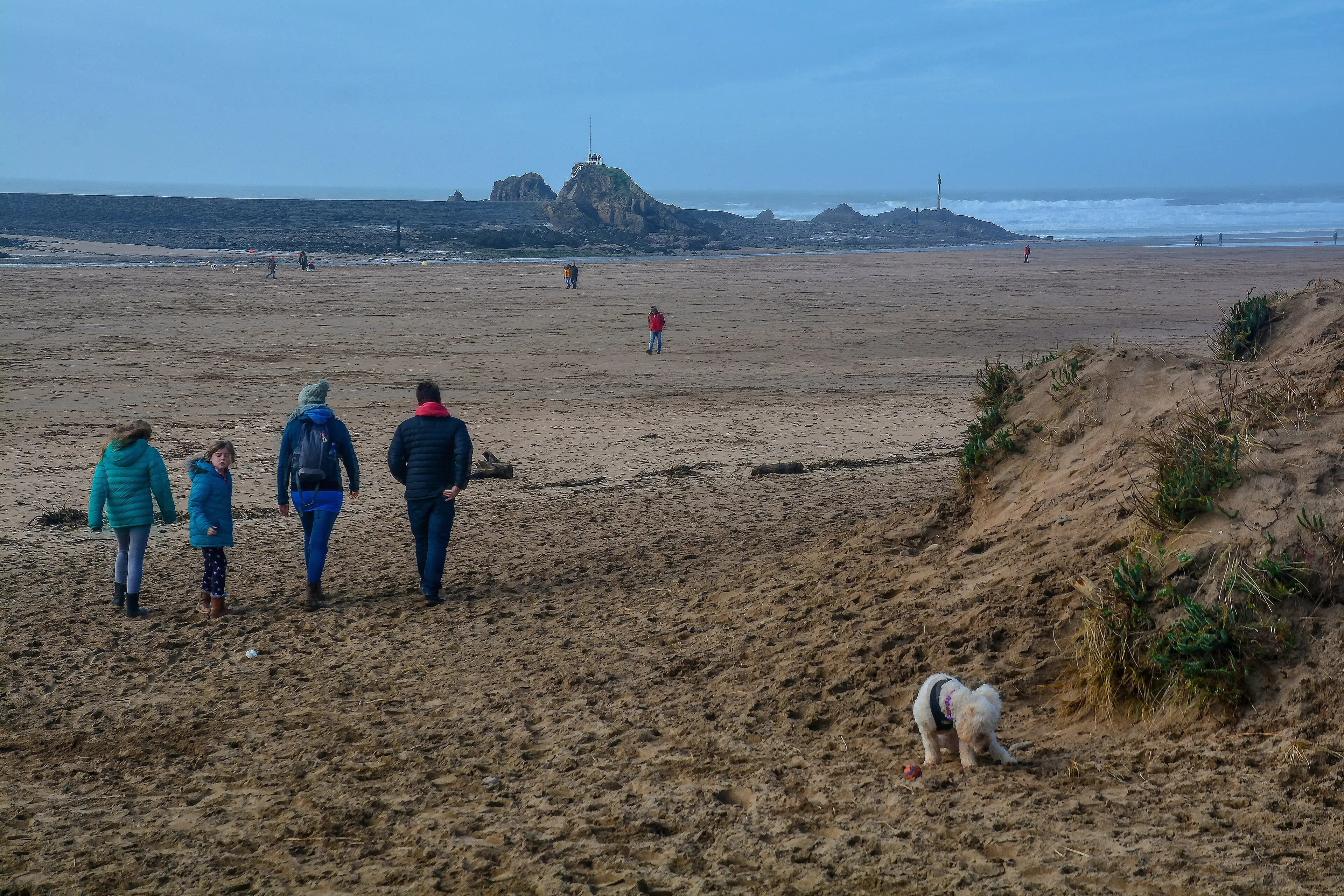 Crooklets Beach in Bude — surfers riding waves with the town visible behind, a classic north Cornwall surf scene.