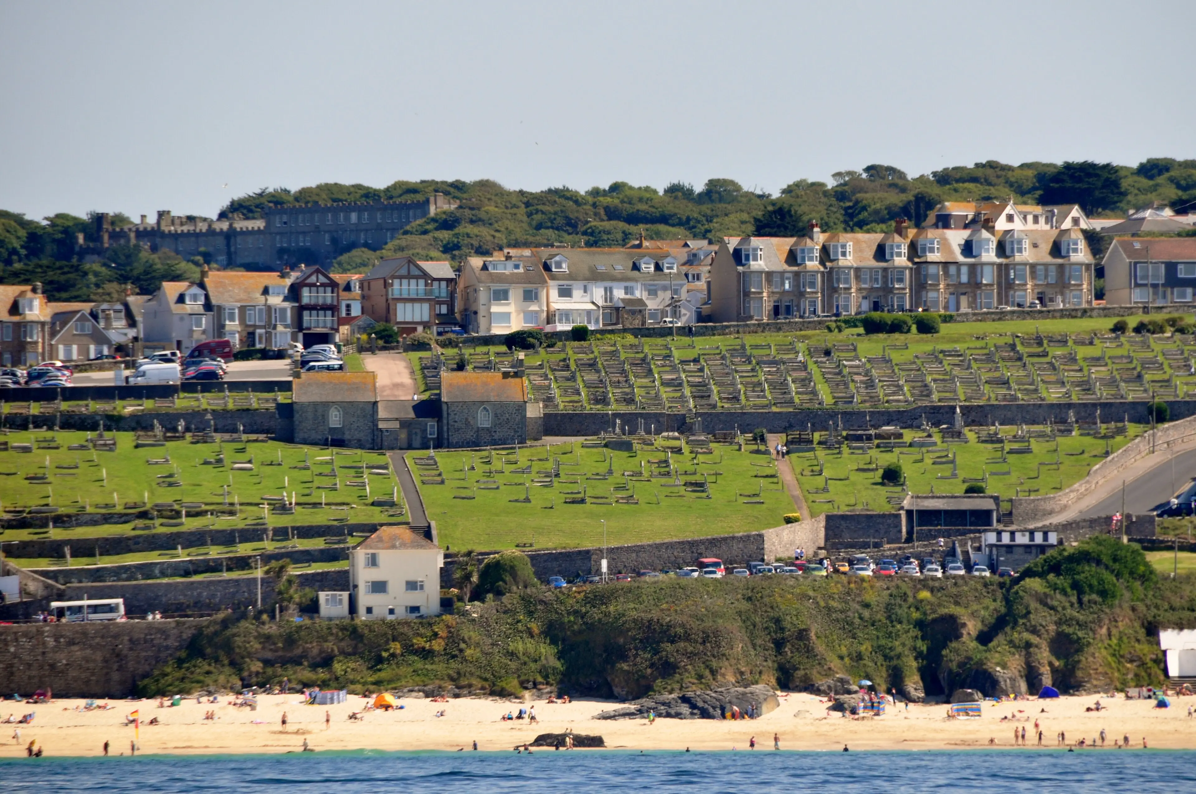 Porthmeor Beach in St Ives — turquoise water and the Tate gallery on the headland above, with surfers in the whitewash.