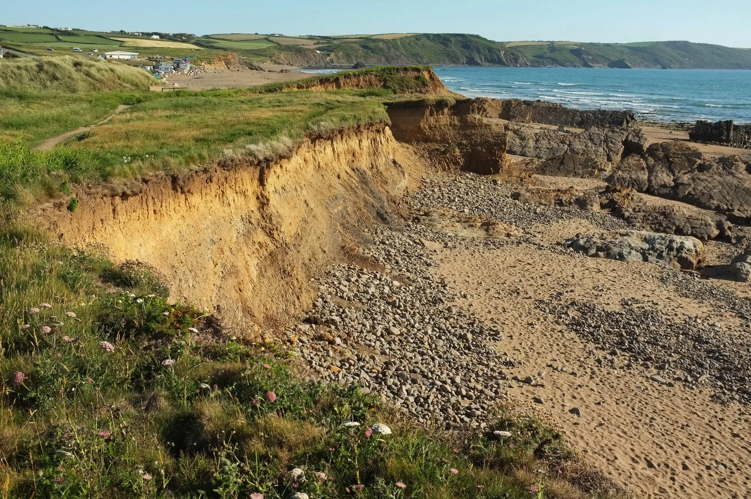 Coastline north of Widemouth Bay — folded rock strata and clifftop path above the Atlantic.